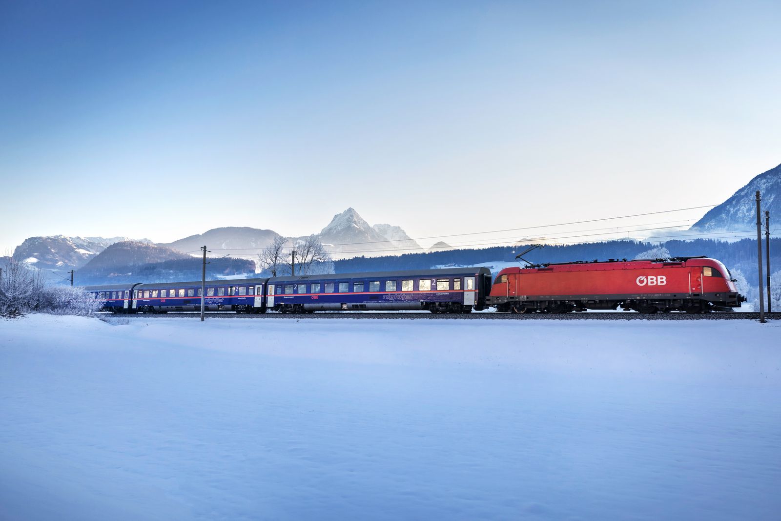 Train de nuit traversant un paysage enneigé en Autriche